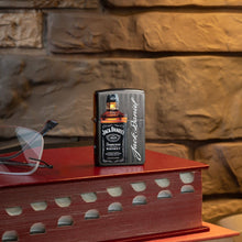 Lifestyle image of Jack Daniel's?« Logo and Bottle Gray Windproof Lighter standing on a red book with glasses next to it