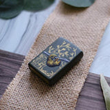 Lifestyle image of Pangolin Design Green Matte Windproof Lighter laying on a burlap sheet on a table