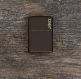 Lifestyle image of Brown Zippo Logo Windproof Lighter laying flat on a wooden background
