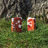 Lifestyle image of Cow Print Design 540 Color Windproof Lighters standing in front of a tree in the grass.