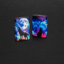 Lifestyle image of two Wolf Howling Design 540 Color Windproof Lighters standing in a grey surface. One lighter is showing the front of the design, and the other lighter is showing the back.