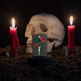 Lifestyle image of Rose Dagger Tattoo Design Black Crackle® Windproof Lighter standing with a skull and lit candles behind it.