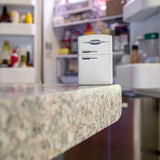 Lifestyle image of Retro Fridge Texture Print White Matte Windproof Lighter standing on a kitchen counter, with an open refrigerator in the background.