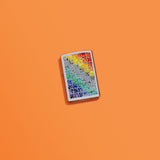 Lifestyle image of Fusion Pattern Design High Polish Chrome Windproof Lighter laying on an orange background.
