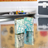 Lifestyle image of two Laser 360° Tattoo Theme Design High Polish Teal Windproof Lighters standing on a table with tattoo equipment.